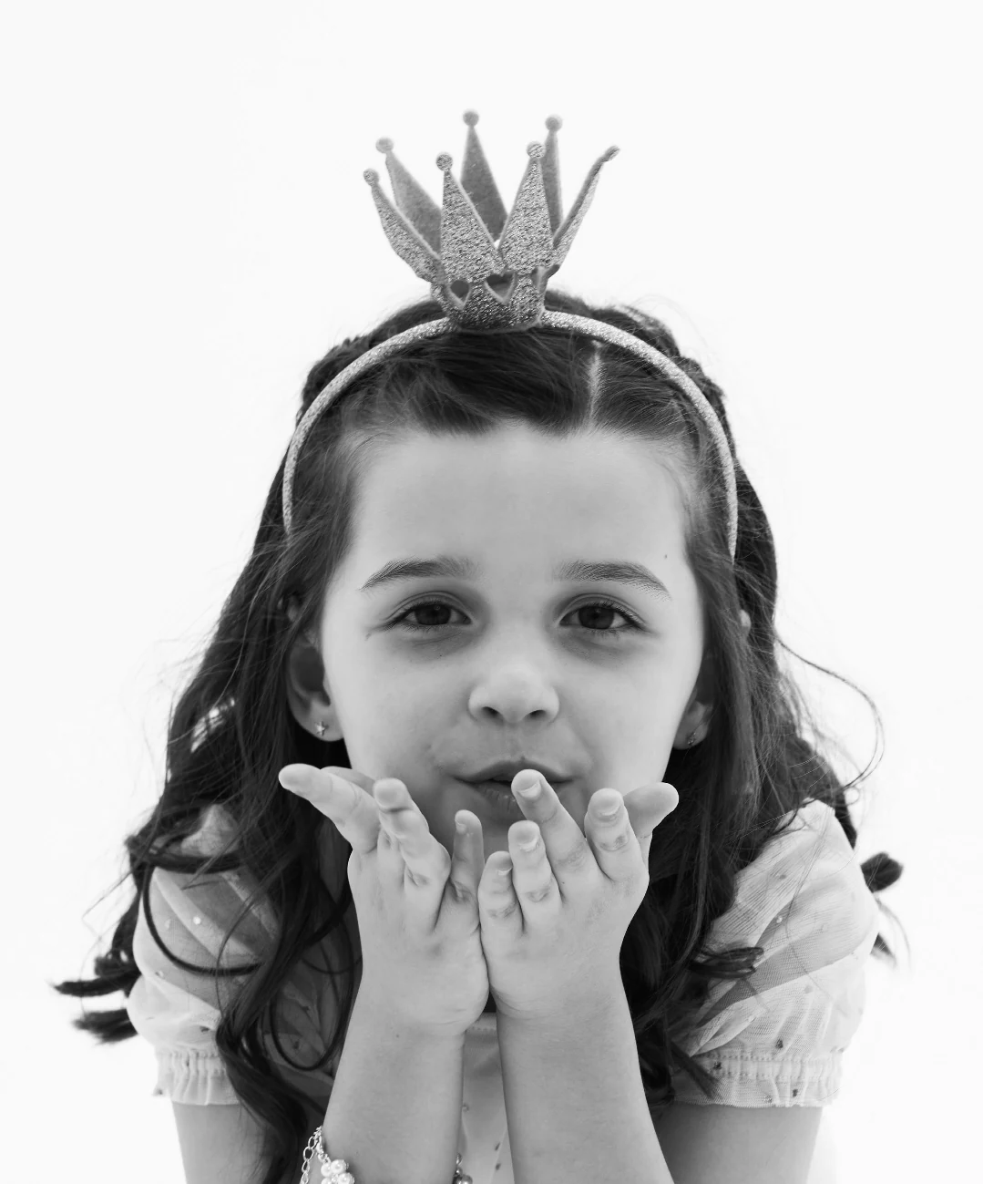 A girl in a paper crown, blowing a kiss
